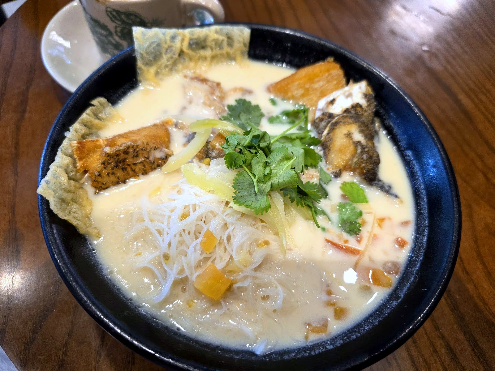 bowl of milky broth fish noodle soup on wooden table